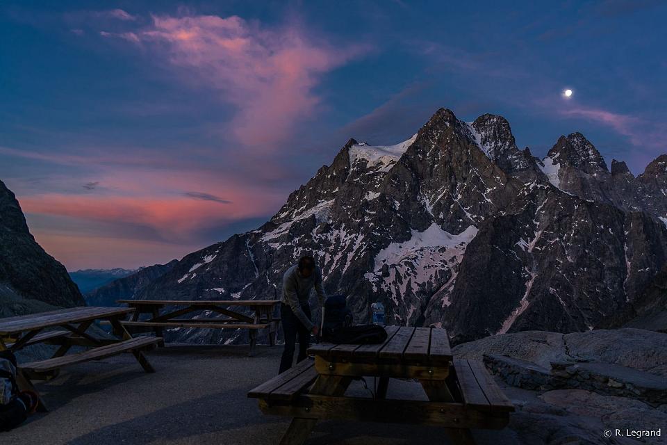 Une superbe photo du crépuscule sur la terasse d'un refuge avec une vue sur le massif des écrins